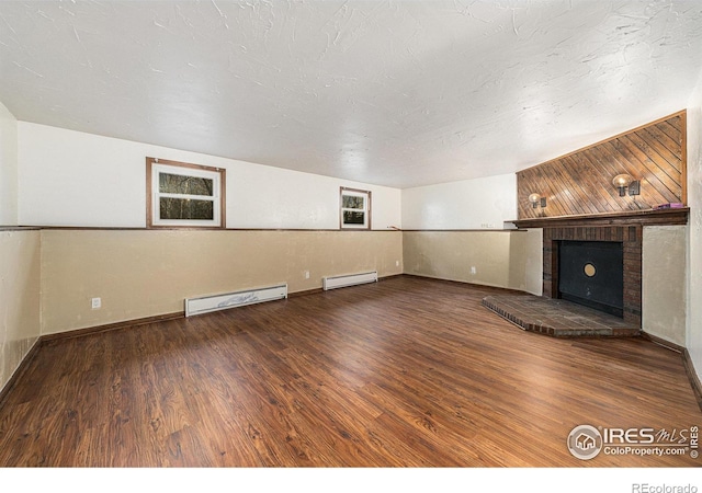 unfurnished living room featuring hardwood / wood-style floors, a baseboard radiator, a textured ceiling, and a brick fireplace