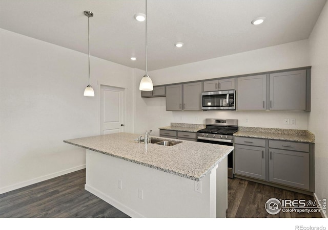 kitchen with gray cabinetry, sink, light stone countertops, appliances with stainless steel finishes, and decorative light fixtures