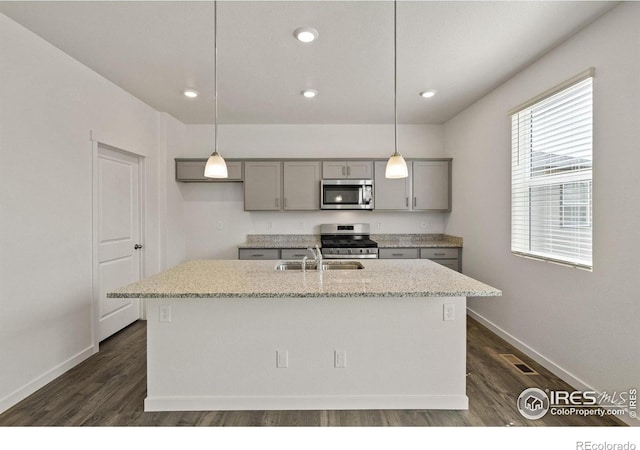 kitchen with hanging light fixtures, gray cabinetry, a center island with sink, and stainless steel appliances