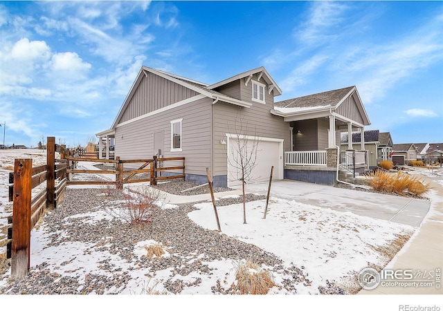 view of snowy exterior featuring a porch and a garage