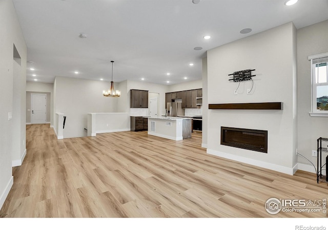 unfurnished living room with an inviting chandelier and light hardwood / wood-style flooring