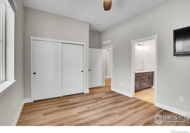 unfurnished bedroom with a closet, ensuite bath, ceiling fan, and light hardwood / wood-style floors