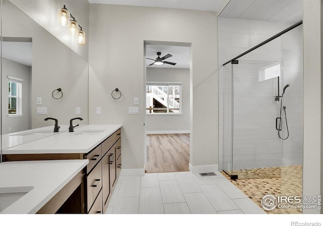 bathroom featuring ceiling fan, a shower with door, vanity, and a healthy amount of sunlight