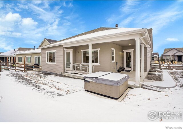 snow covered house featuring a hot tub