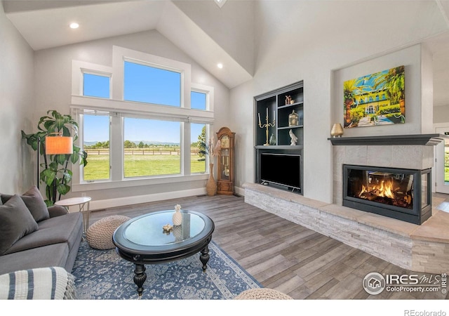 living room featuring built in shelves, a towering ceiling, and hardwood / wood-style floors