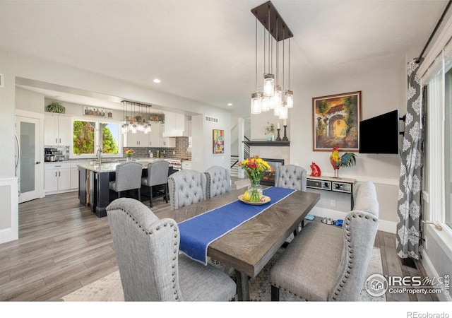 dining room with light hardwood / wood-style floors, sink, and a tile fireplace