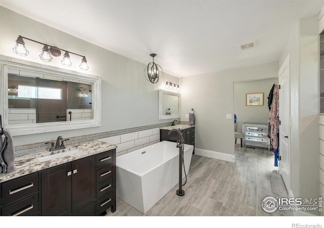 37001 Soaring Eagle Cir, Severance, CO 80550 - bathroom featuring a freestanding tub, two vanities, wood finished floors, tiled shower, and tile walls