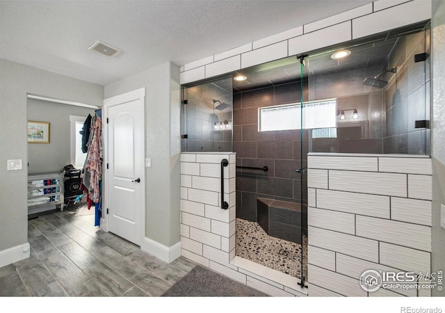 bathroom with a textured ceiling and tiled shower