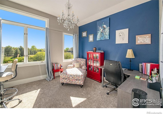 carpeted home office featuring a chandelier