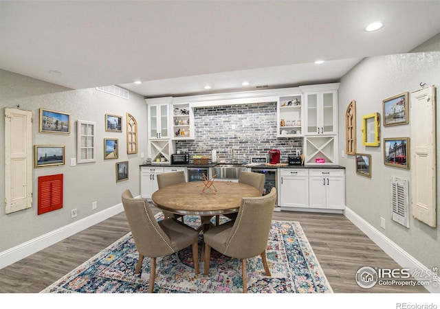 dining area featuring bar area, beverage cooler, and wood-type flooring