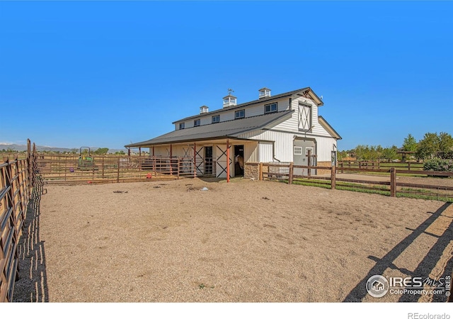 back of property featuring a rural view and an outbuilding