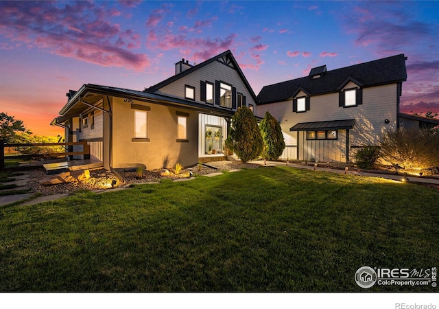 37001 Soaring Eagle Cir, Severance, CO 80550 - back of property at dusk featuring a lawn, a chimney, and stucco siding
