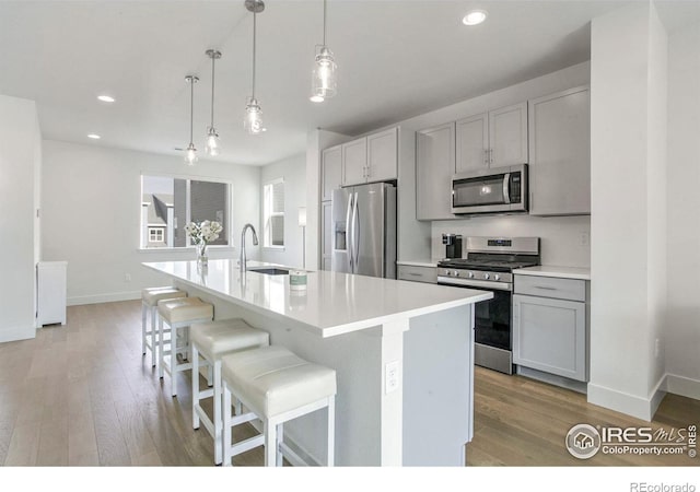 kitchen featuring sink, an island with sink, pendant lighting, and appliances with stainless steel finishes