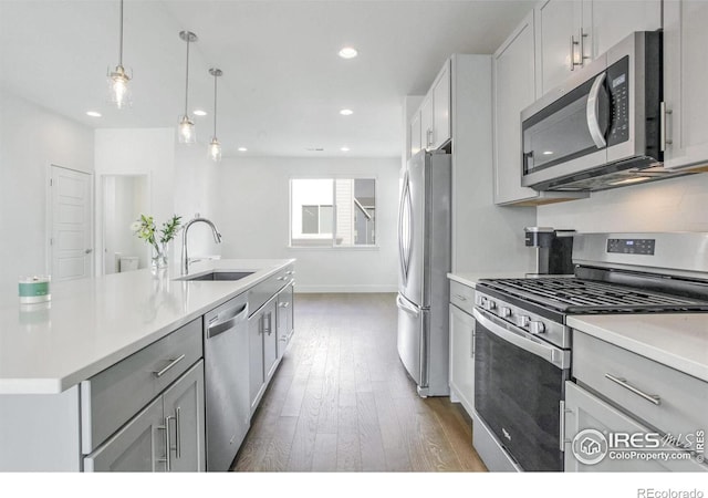 kitchen featuring sink, stainless steel appliances, dark hardwood / wood-style flooring, an island with sink, and decorative light fixtures