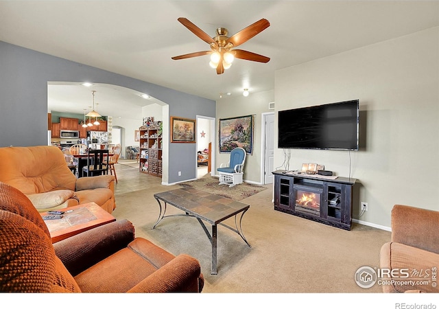 living room with ceiling fan, a fireplace, and light colored carpet