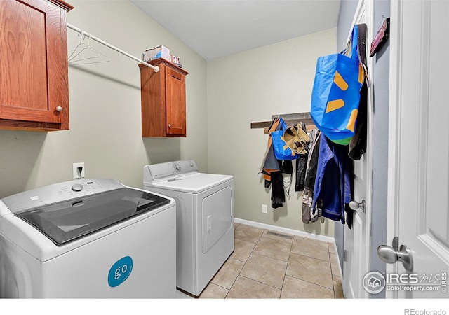 clothes washing area with light tile patterned flooring, cabinets, and independent washer and dryer