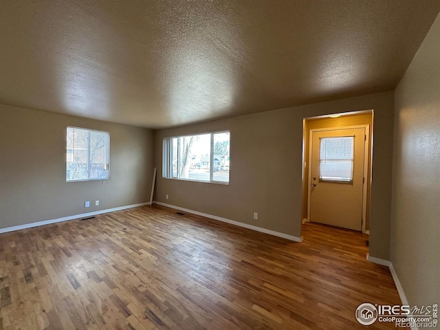 spare room featuring hardwood / wood-style floors and a textured ceiling