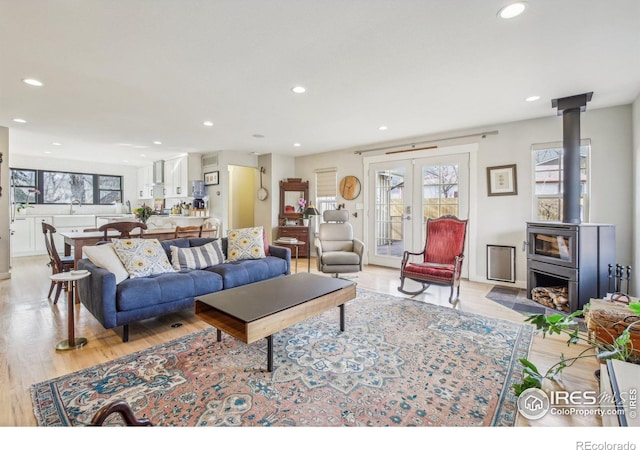 living room with light hardwood / wood-style flooring, a wood stove, sink, and french doors