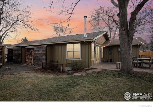 back house at dusk with a lawn and a patio