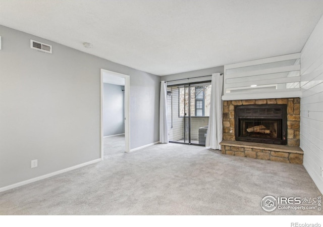 unfurnished living room featuring a stone fireplace and light colored carpet