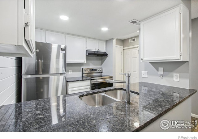 kitchen featuring sink, stainless steel appliances, kitchen peninsula, dark stone counters, and white cabinets