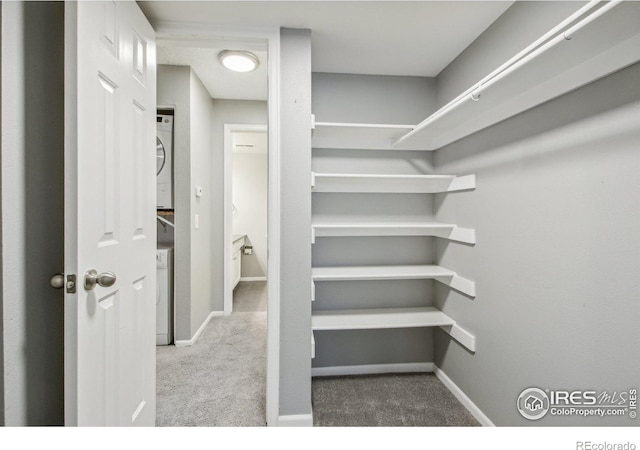 walk in closet featuring stacked washer / dryer and carpet