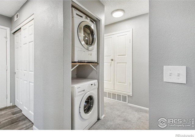 laundry area featuring stacked washing maching and dryer and a textured ceiling