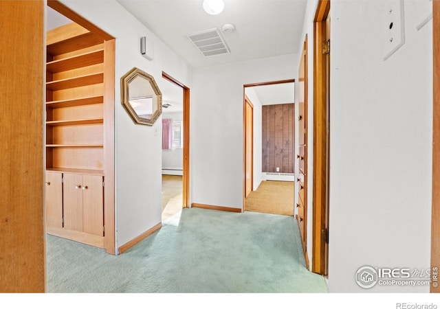 hallway featuring light colored carpet and a baseboard heating unit