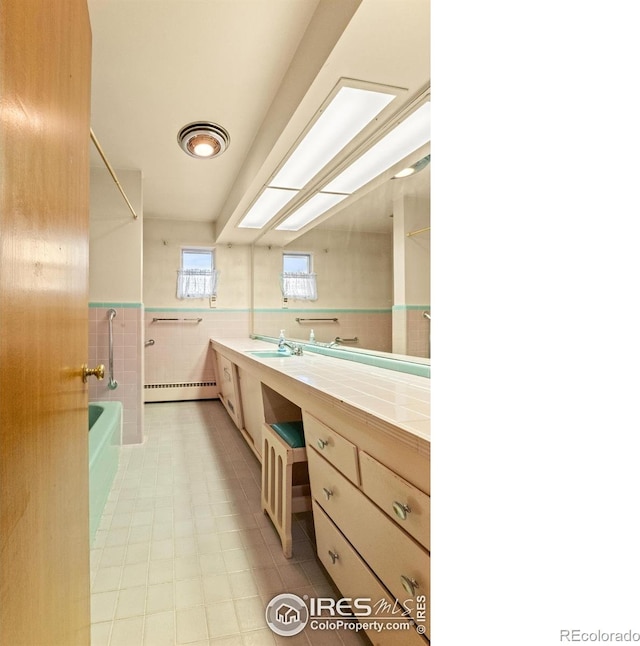 bathroom with vanity, a baseboard radiator, and tile walls