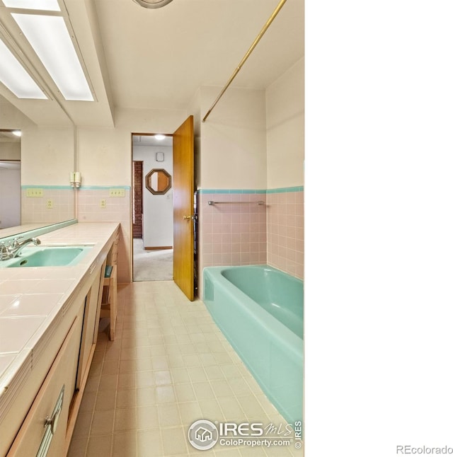 bathroom featuring a bathtub, tile walls, and vanity