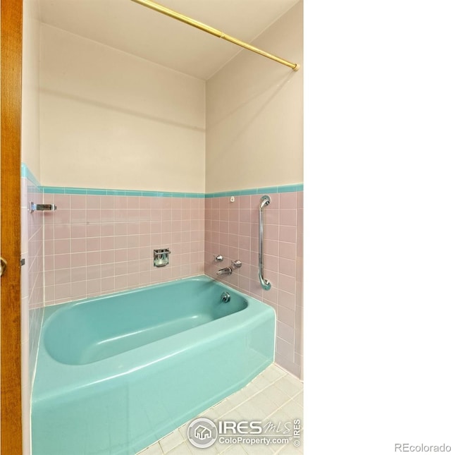 bathroom featuring tile patterned floors, a washtub, and tile walls