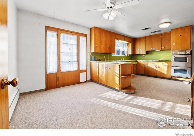 kitchen featuring ceiling fan, stainless steel double oven, a baseboard heating unit, kitchen peninsula, and light carpet