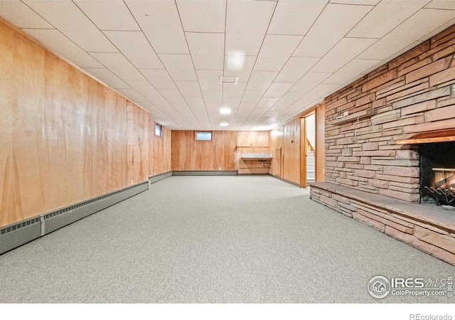 basement featuring baseboard heating, light carpet, and a fireplace