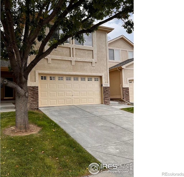 view of front of property featuring a garage, stone siding, driveway, and stucco siding