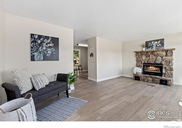 living room with a fireplace, wood-type flooring, and a textured ceiling