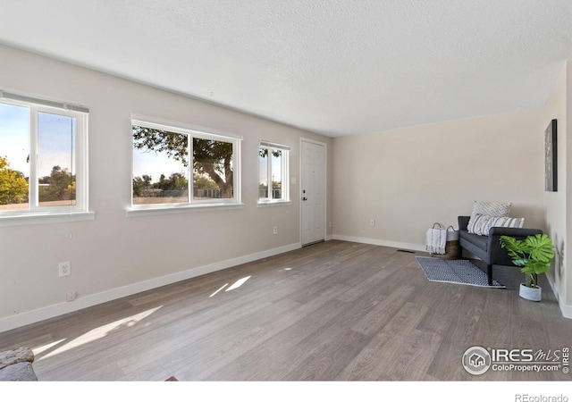 unfurnished living room featuring hardwood / wood-style floors and a textured ceiling