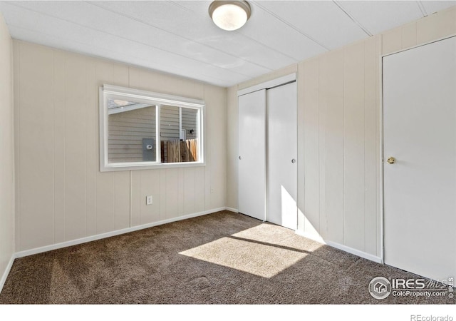 unfurnished bedroom with dark carpet and a closet