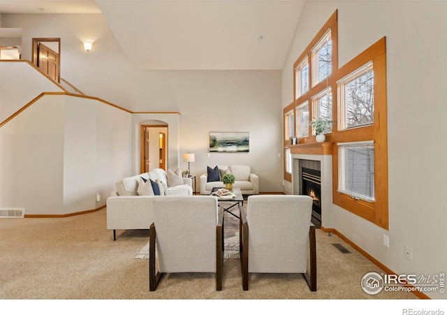 living room featuring high vaulted ceiling, a fireplace, and light carpet