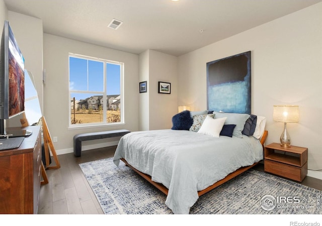 bedroom featuring baseboards, visible vents, and wood finished floors