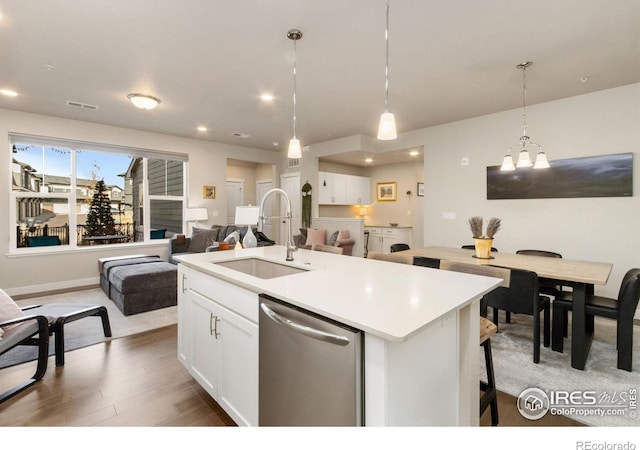 kitchen with open floor plan, white cabinetry, a sink, and stainless steel dishwasher