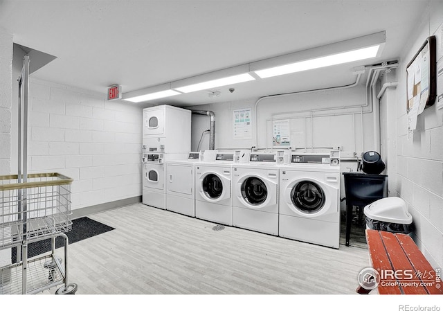 shared laundry area featuring washer and clothes dryer, concrete block wall, and stacked washer / drying machine