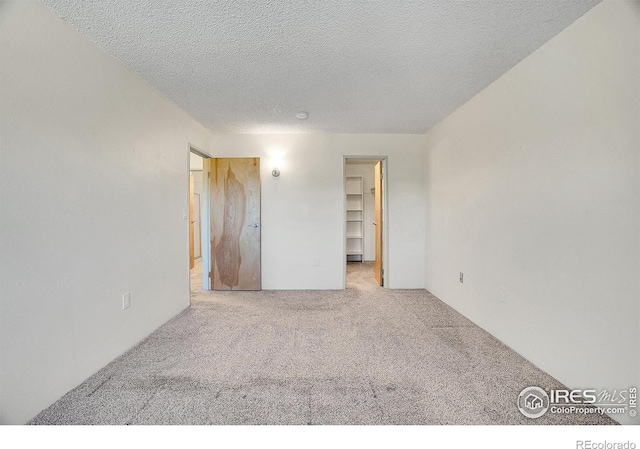 unfurnished bedroom featuring carpet floors, a textured ceiling, and a spacious closet