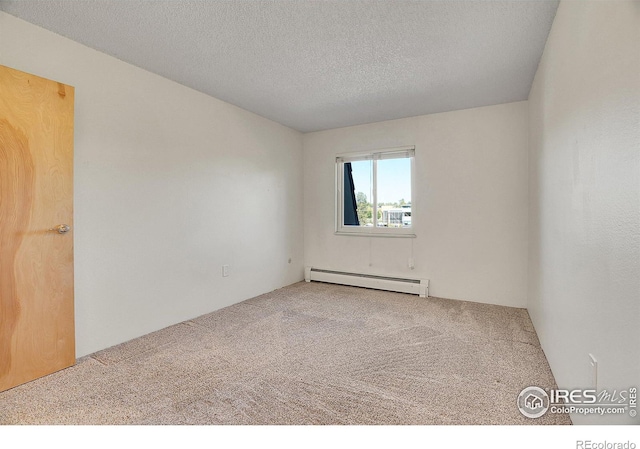 carpeted empty room with baseboard heating and a textured ceiling