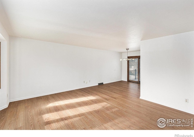 spare room featuring hardwood / wood-style flooring and a notable chandelier