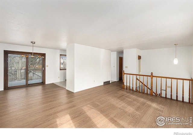 unfurnished room with a notable chandelier and wood-type flooring