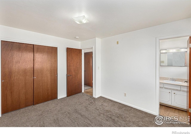 unfurnished bedroom with a closet, ensuite bath, light carpet, and sink