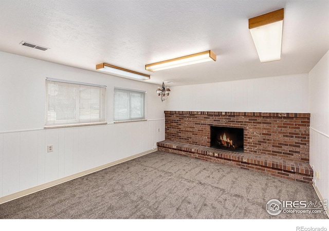 unfurnished living room with carpet flooring, a fireplace, and a textured ceiling