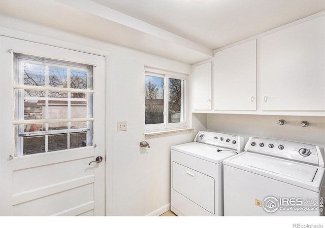 clothes washing area featuring cabinets, a wealth of natural light, and washing machine and clothes dryer