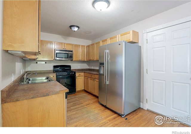 kitchen with sink, light wood-type flooring, light brown cabinets, and appliances with stainless steel finishes