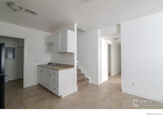 kitchen featuring white cabinetry, sink, and light tile patterned flooring